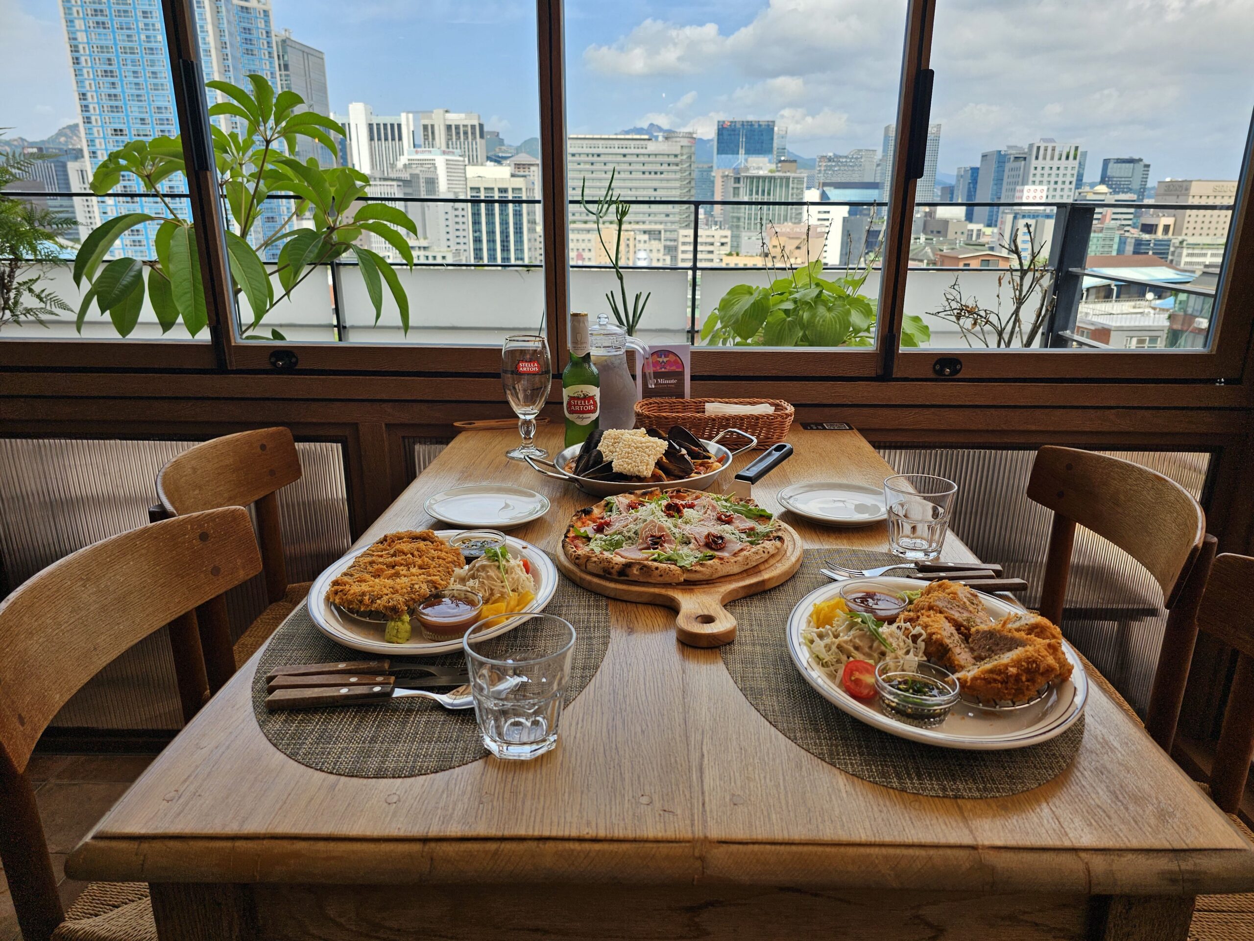 Window-side shared dining table with several dishes and city view