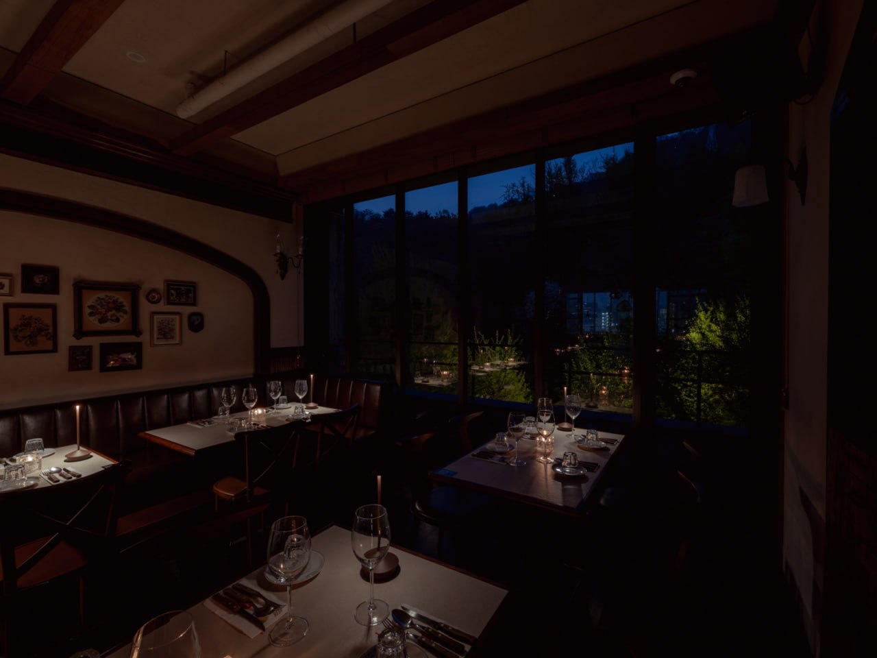 Evening dining room with candlelit tables beside large windows at CHOTBOOL 1978